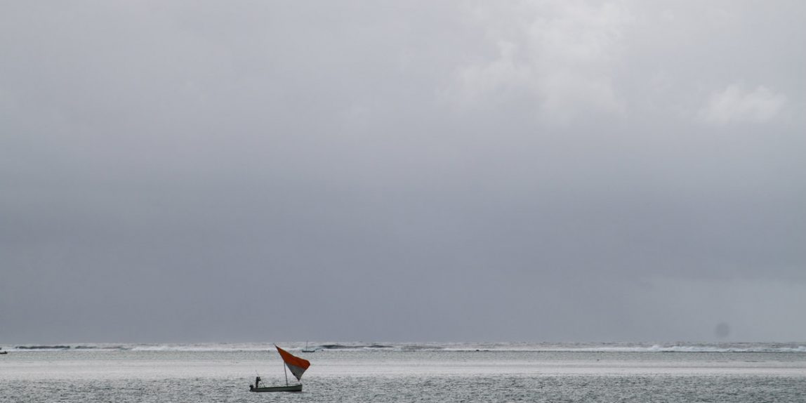 A single-sailed fishing boat in dawn light